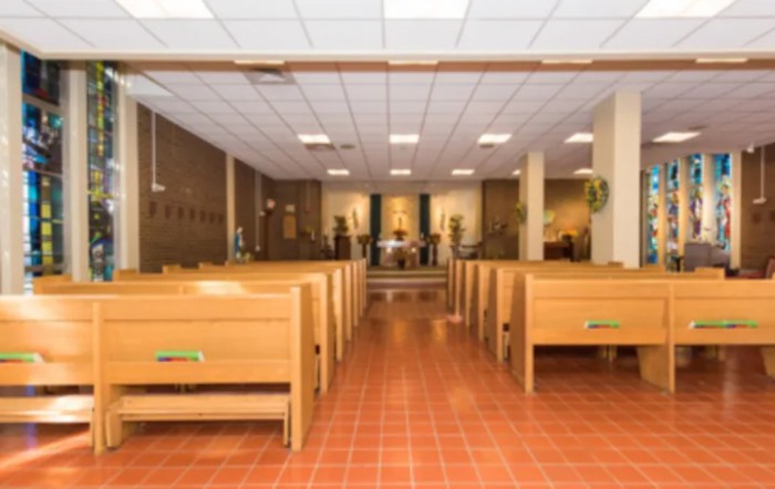 An interior view of a church with wooden pews and an altar at the front.