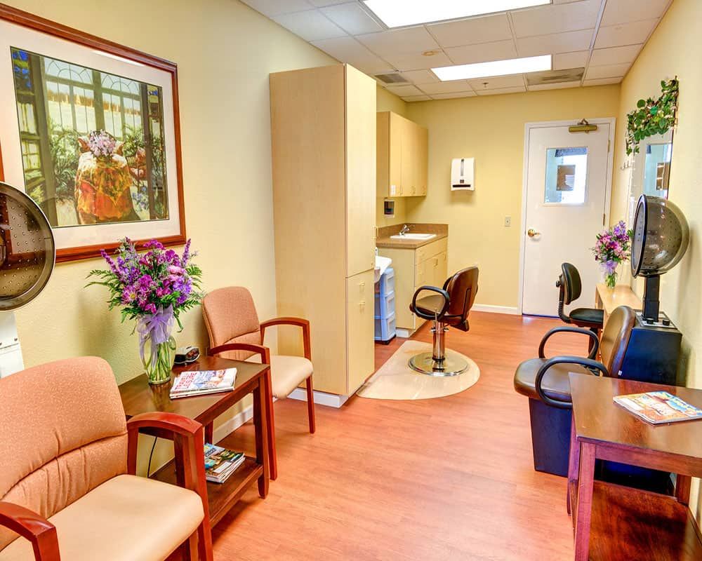 A cozy waiting area with comfortable chairs, a floral arrangement, and a decorative painting on the wall.