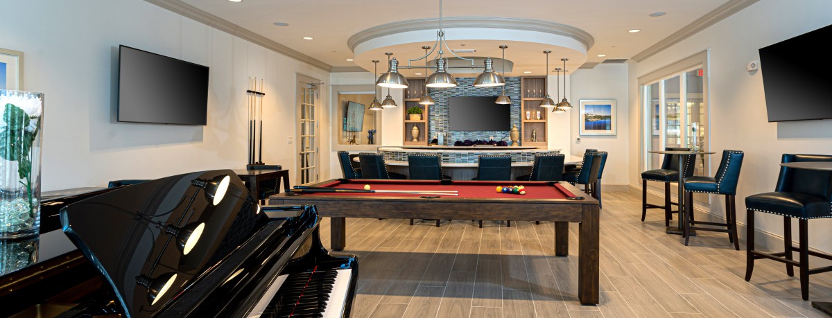 A luxurious game room featuring a pool table, piano, and a stylish bar area with modern lighting.