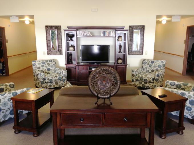 A cozy living room with floral armchairs, a wooden entertainment center, and decorative pieces.