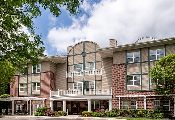 A multi-story residential building with brick and siding exterior under a partly cloudy sky.