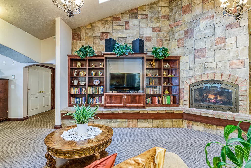 A cozy living room featuring a stone wall with built-in bookshelves, a television, and a fireplace.