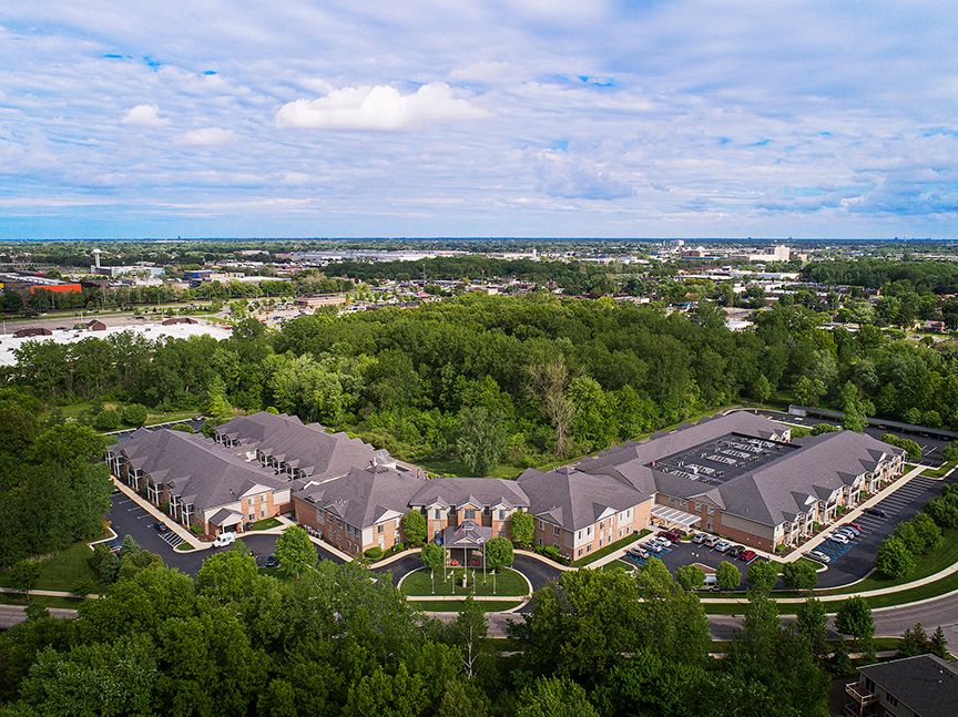 Aerial view of a building complex surrounded by trees and a clear sky.