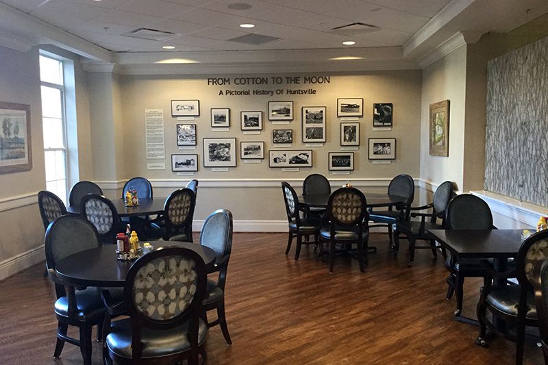 A cozy dining area with tables and chairs, featuring a wall adorned with framed photographs.