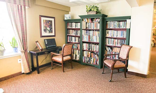 A cozy reading room with bookshelves, a computer desk, and seating.