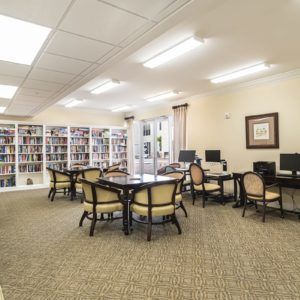 A cozy library space with bookshelves, computers, and tables for reading.