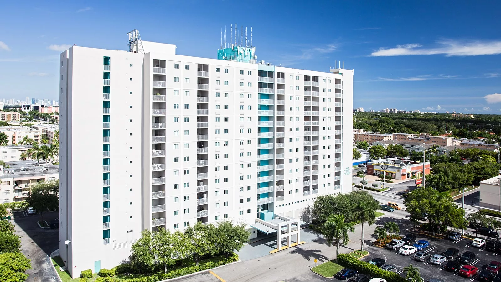 A tall hotel building with palm trees and a clear blue sky.