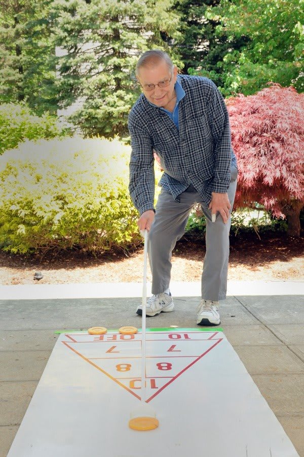 An elderly person playing a game of shuffleboard outdoors.