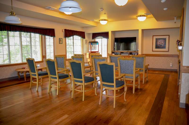 A well-lit conference room with arranged chairs and wood flooring.