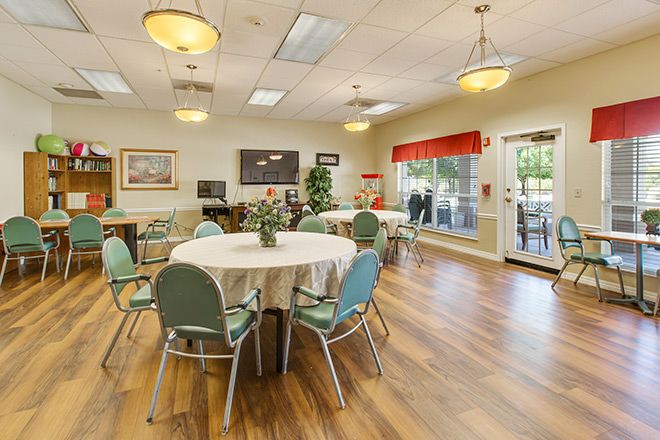 A well-lit dining area with round tables and green chairs, featuring a welcoming atmosphere.