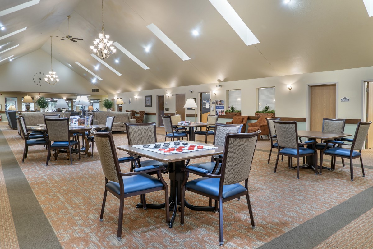 A spacious dining area with neatly arranged tables and chairs, well-lit by modern ceiling lights.