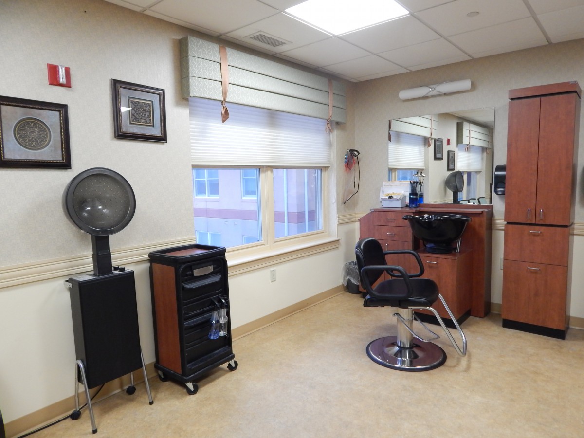 An empty hair salon with a styling chair and mirror setup.