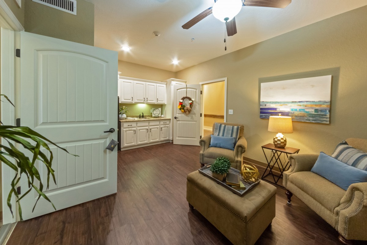 A cozy living area with an open kitchen, featuring comfortable seating and warm lighting.