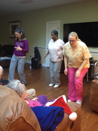 Caregivers interacting through dance with elderly individuals, promoting joy and connection in a community setting.