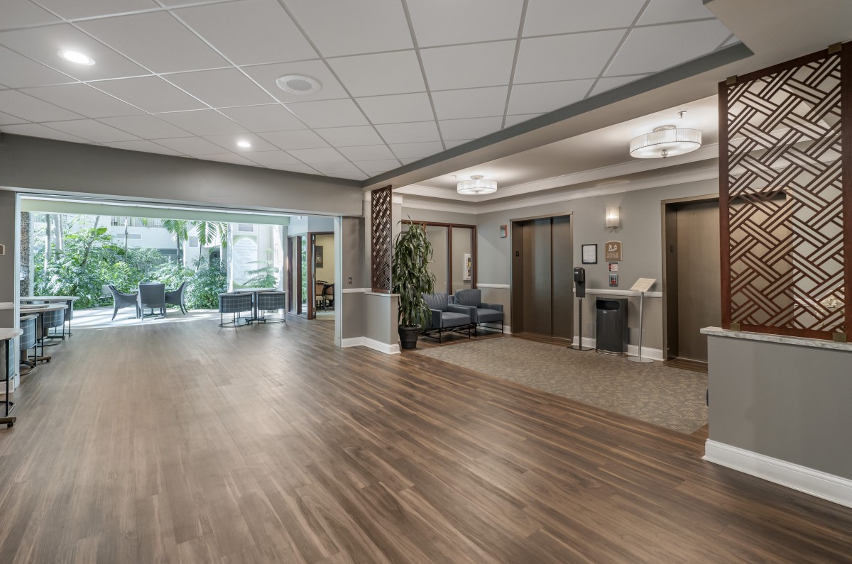 A modern lobby area with hardwood flooring and natural light, featuring elevators and a waiting area.