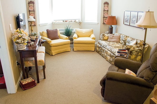 A cozy living room with comfortable armchairs and a sofa, decorated in warm tones.