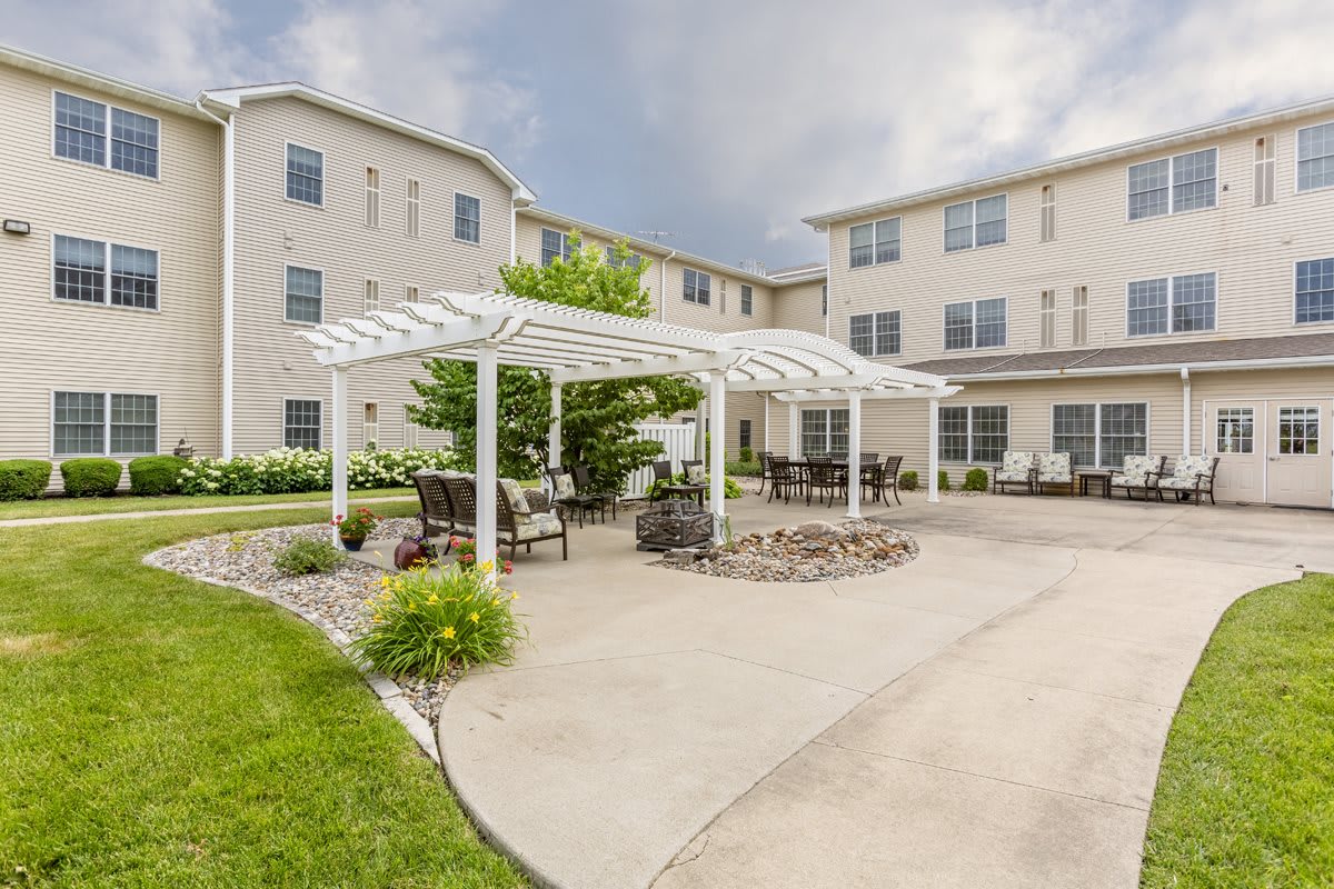 A well-maintained courtyard with a pergola and outdoor seating in front of an apartment building.