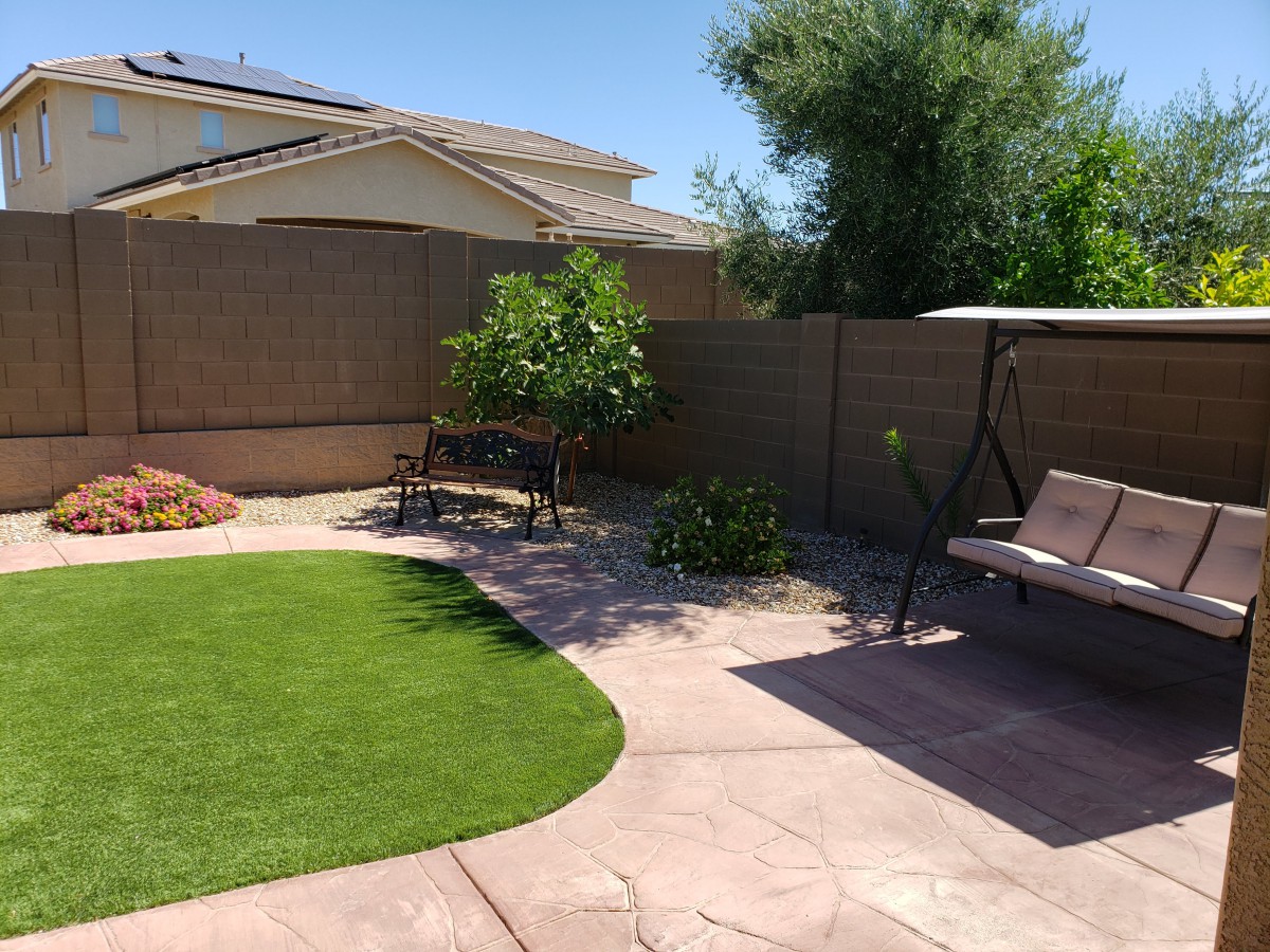 A tranquil backyard with a swing, bench, and artificial grass.