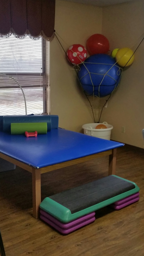 A well-organized physical therapy room equipped with a therapy table and colorful exercise balls.