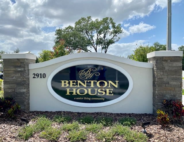 A sign for Benton House, featuring elegant landscaping and a clear blue sky.