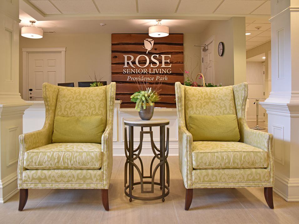 A welcoming lobby area featuring two comfortable chairs and a wooden sign with the name 'Rose' on the wall.