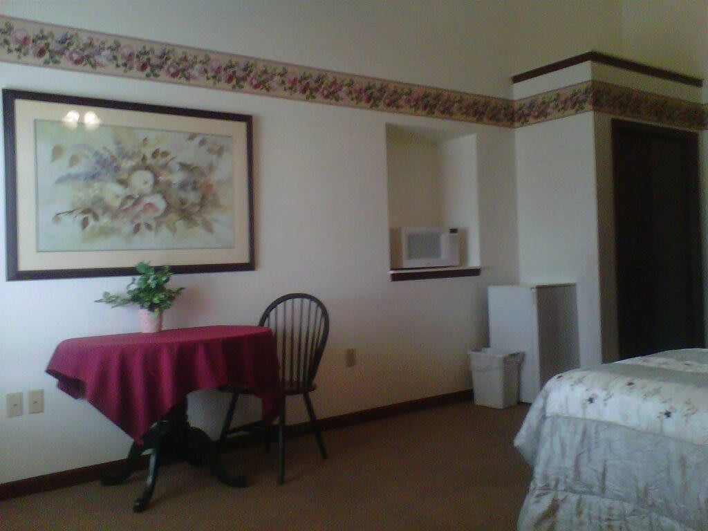 A cozy room with a small table, chair, and wall painting.