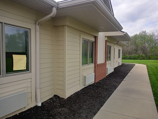 A corner view of a modern building with light siding and a landscaped area.