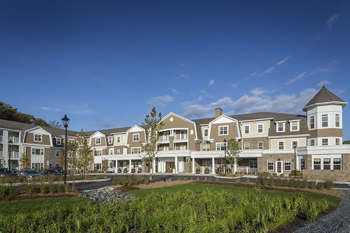 A three-story residential building with landscaping under a clear blue sky.