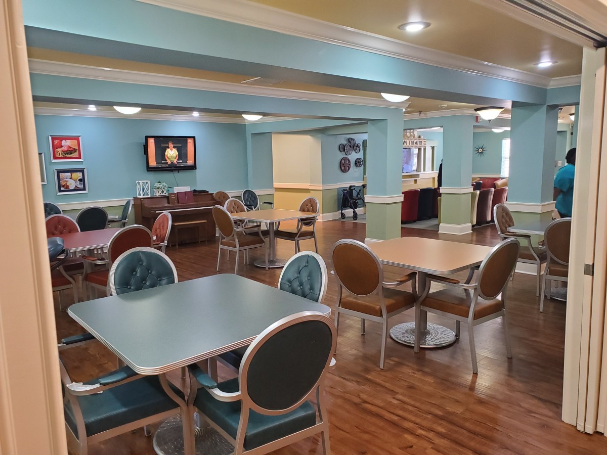 A cozy indoor dining area with tables, chairs, and a television, featuring soft lighting and inviting decor.