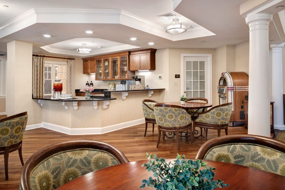 A cozy kitchen and dining area featuring elegant furnishings, warm lighting, and a wooden floor.