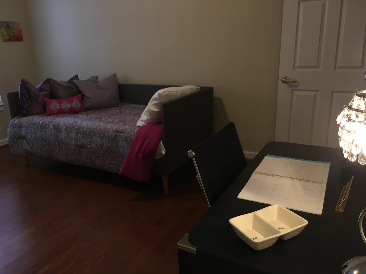 A room featuring a sofa, a table with a takeout container, and a chair.