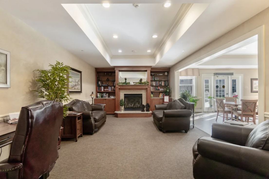 A cozy living room with a fireplace, leather chairs, and bookshelves.