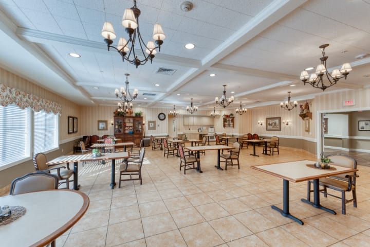 A spacious dining area with elegant chandeliers and neatly arranged tables and chairs.