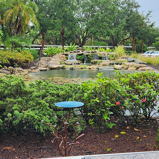 A serene view of a landscaped park featuring a tranquil pond and lush greenery.