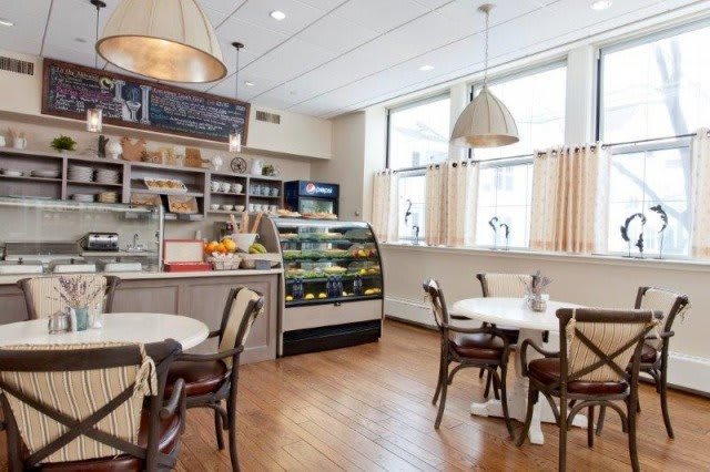 A cozy cafe interior with tables, chairs, a menu board, and a display case.