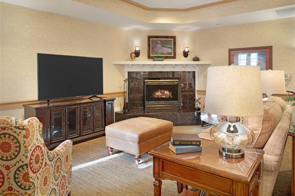 A cozy living room with a fireplace and television, featuring comfortable furniture and tasteful decor.