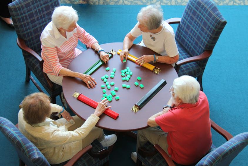 A group of seniors playing a game of mahjong at a table.