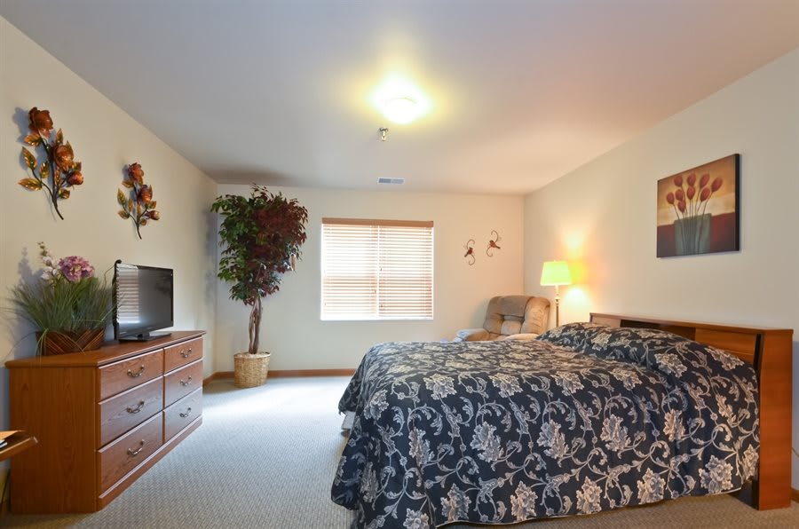A cozy bedroom with a large bed, wooden furniture, and soft lighting.