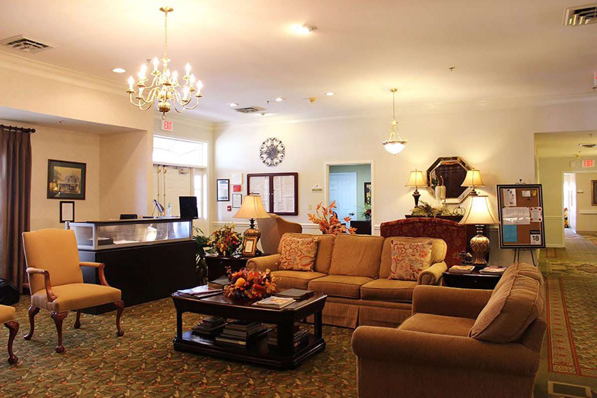 A cozy living room with a chandelier, sofas, and a reception desk.