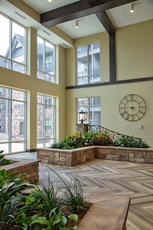 A spacious lobby with large windows, natural light, and indoor plants.