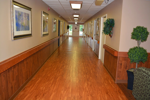 A well-lit hallway featuring wooden flooring and decorative artwork along the walls.