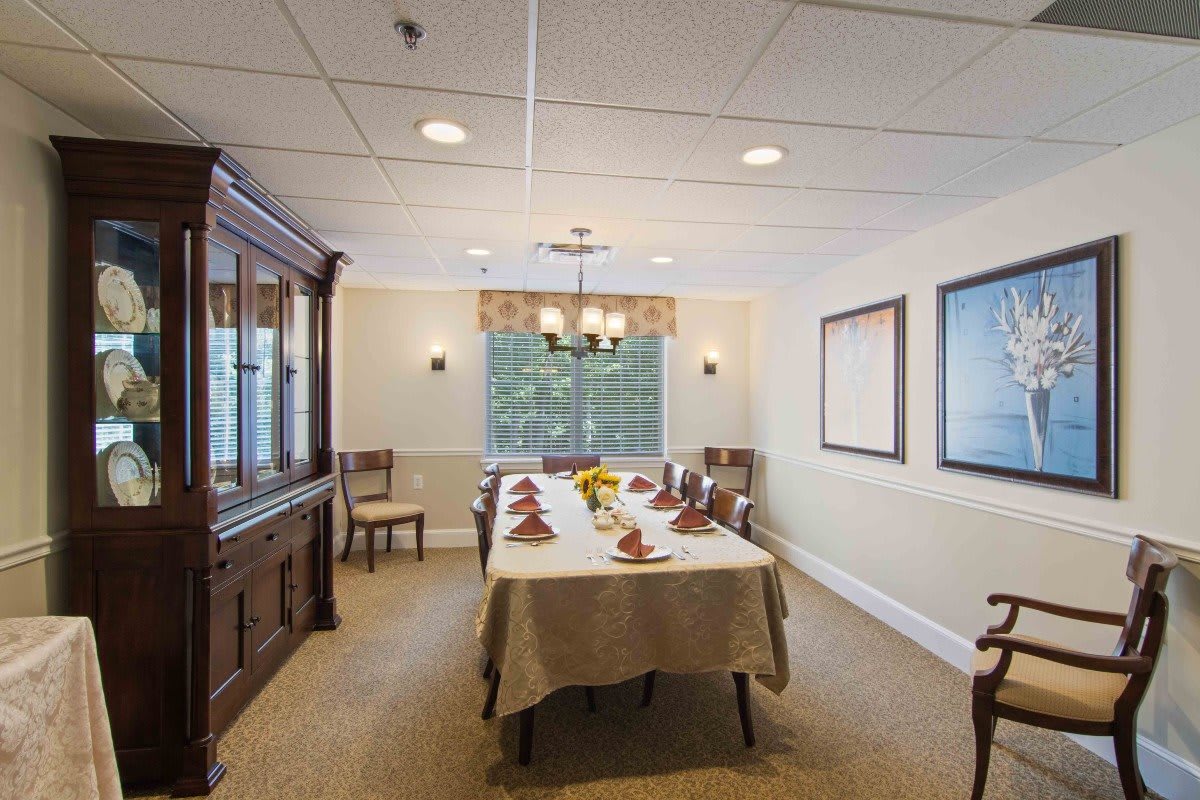 A formal dining room with a large table set for a meal, featuring a chandelier and classic decor.