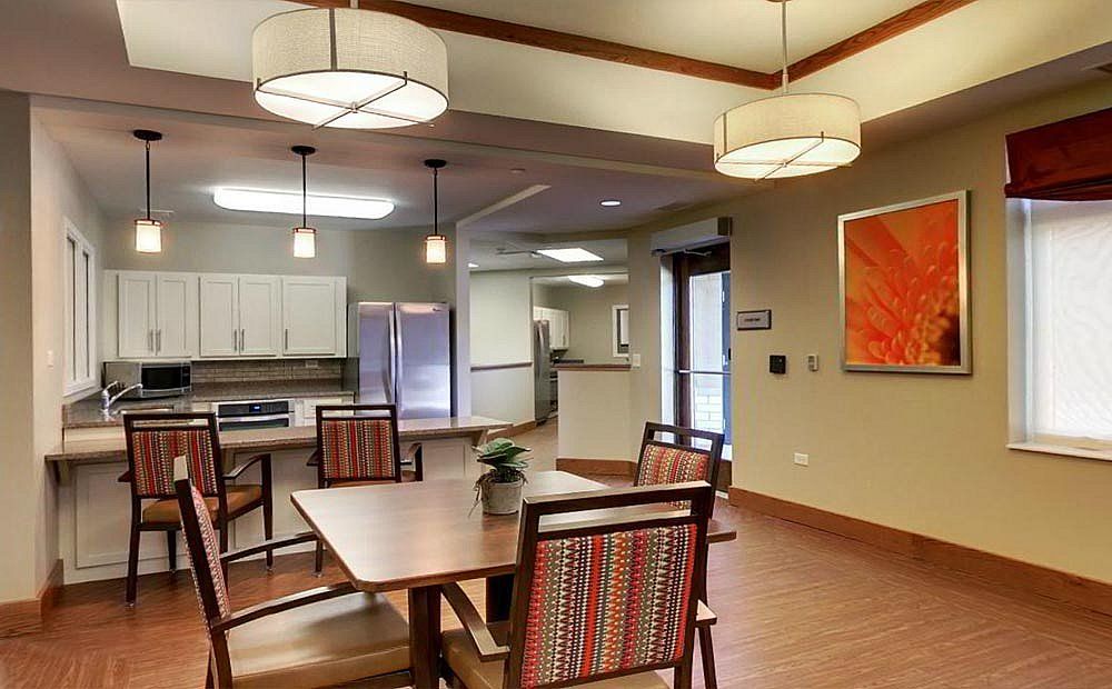 A modern dining area with a connected kitchen, featuring contemporary lighting and furniture.