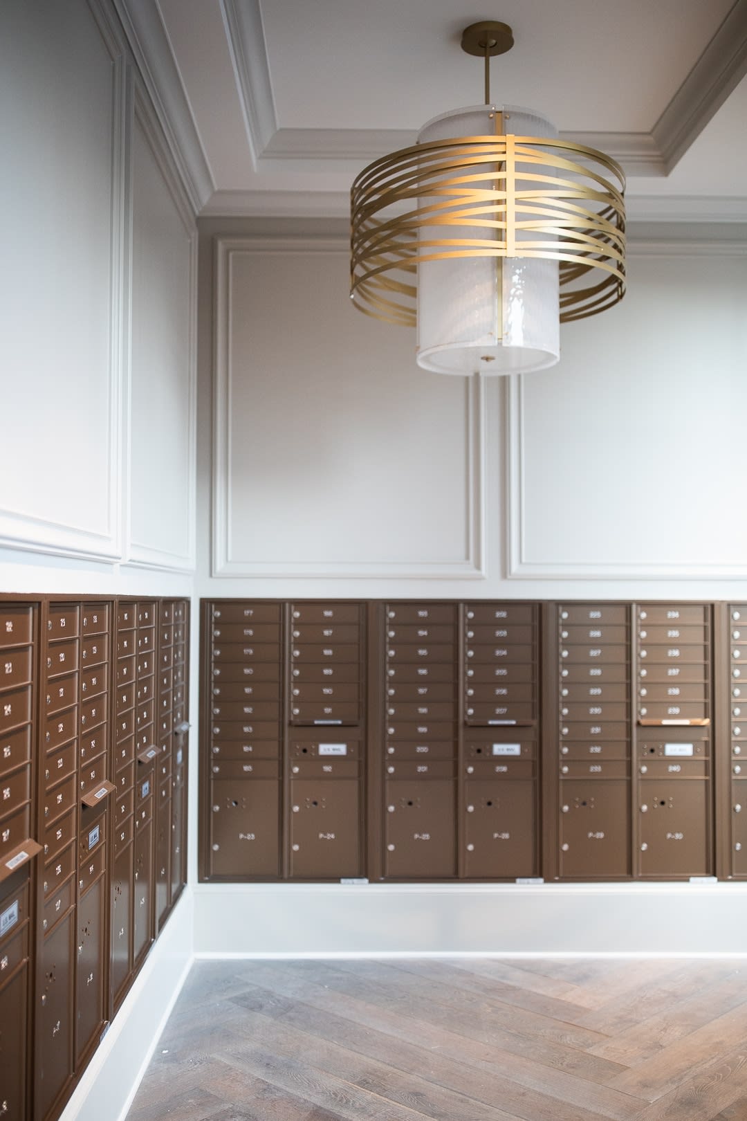 A modern interior with rows of mailboxes and a contemporary light fixture.