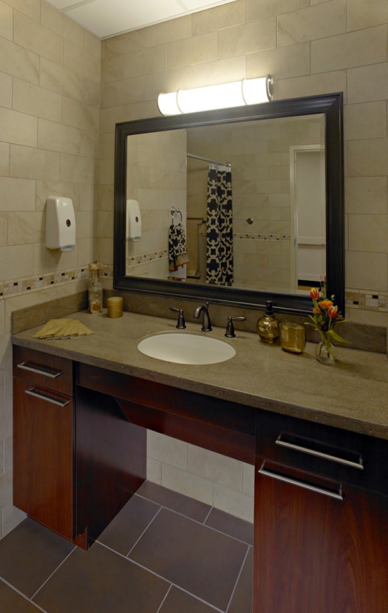 A modern bathroom featuring a sleek countertop with a sink and a large framed mirror.