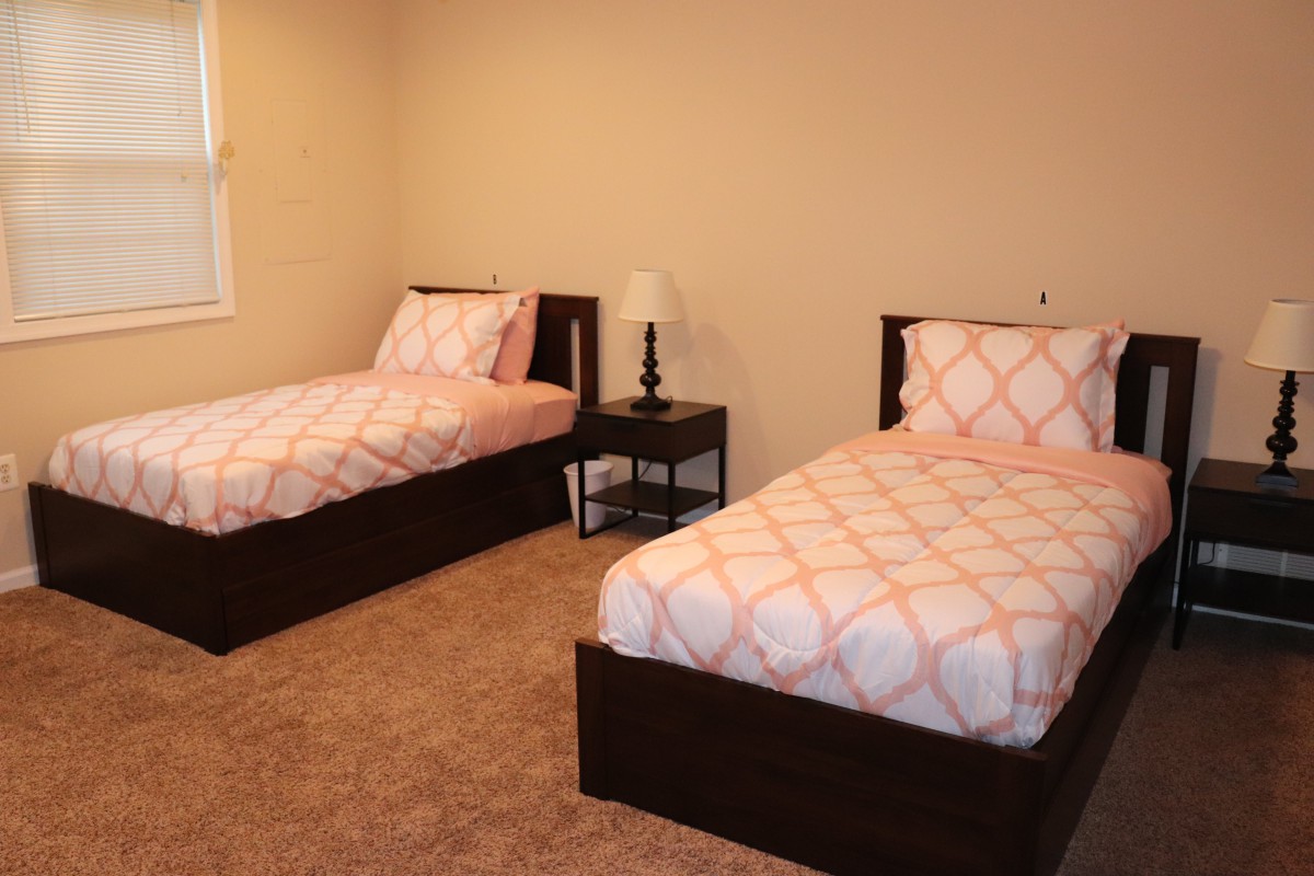 A simple bedroom with two twin beds and a nightstand.
