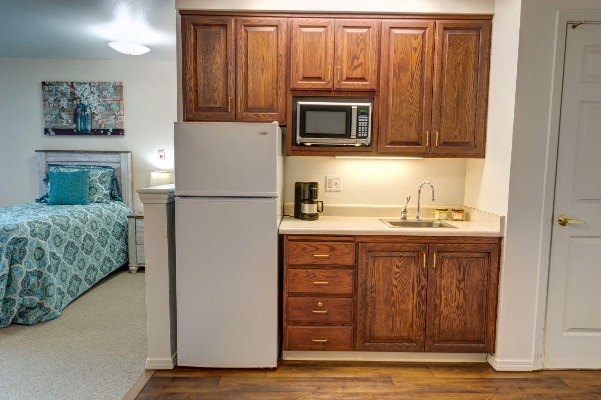 Compact kitchen with wooden cabinets, equipped with a fridge, microwave, and small appliances.