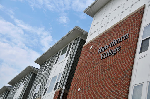 A modern residential building known as Hawthorne Village, showcasing a blend of brick and contemporary architectural design against a cloudy sky.
