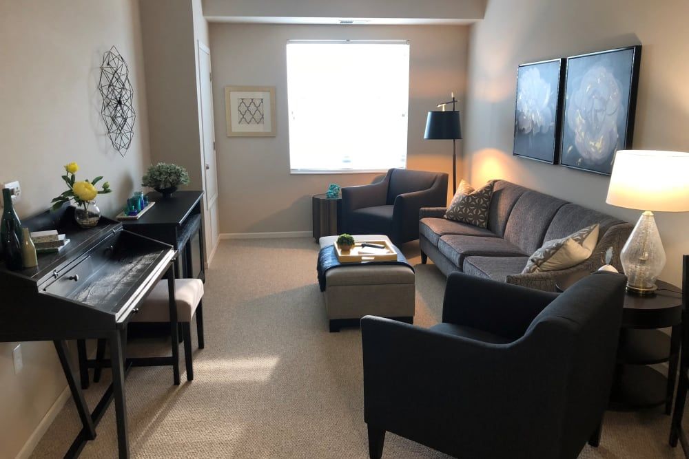 A cozy living room with a sofa, armchairs, a piano, and a coffee table.