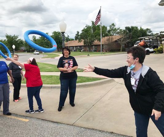 A group of people playing a ring toss game outdoors.